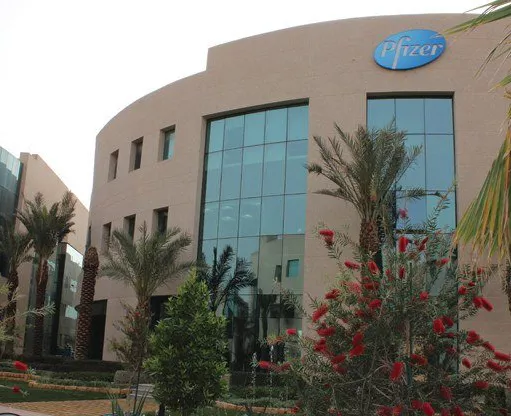 The Business Gate features a contemporary curved design with large glass windows, framed by palm trees and landscaped gardens, offering a distinguished corporate setting.