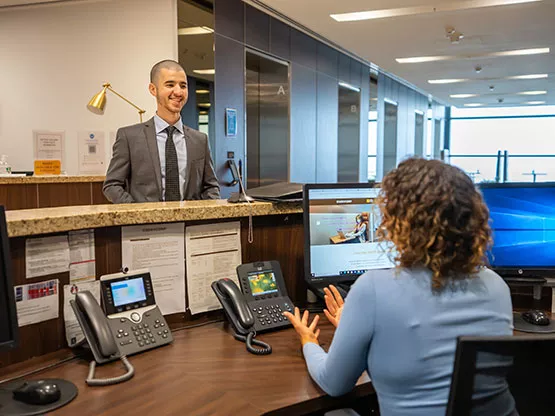 Servcorp serviced office reception, where a well-dressed client is greeted by a friendly receptionist in a sleek, modern front desk area