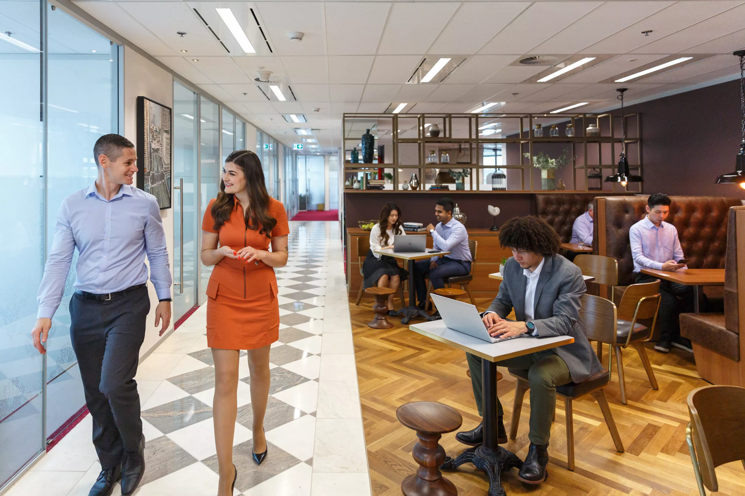 Clients at coworking in Servcorp seated in stylish booth seating and collaborative spaces, actively using devices.