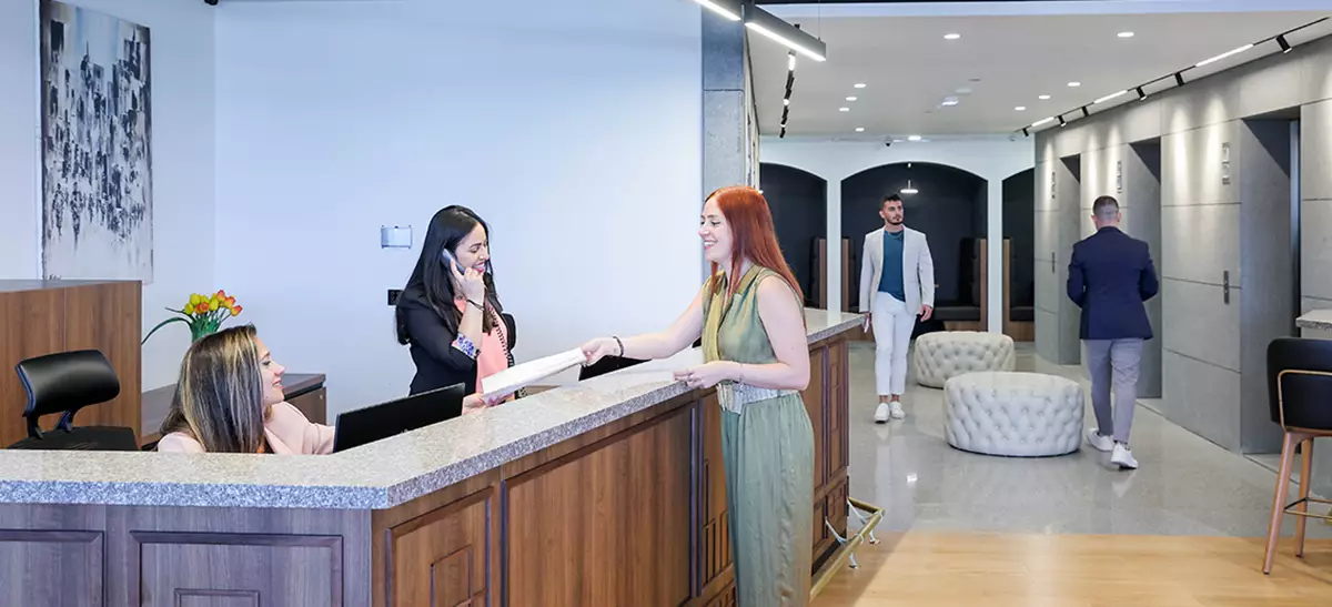Coworking Space at Qubic Square with receptionist handling calls, mail, and clients working at hot desks.