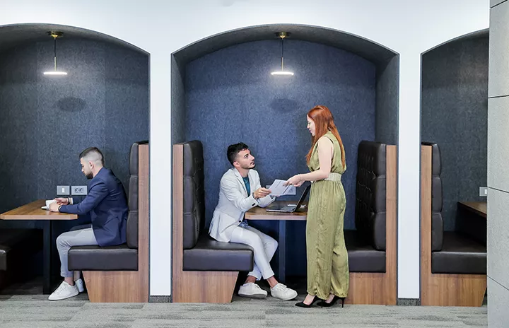 Clients at coworking in Servcorp seated in stylish booth seating and collaborative spaces, actively using devices.