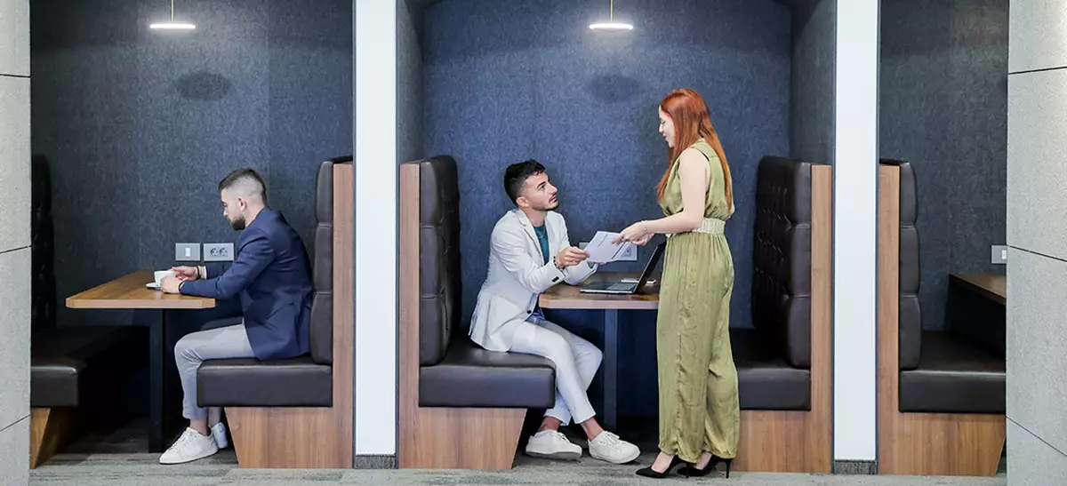 Clients at coworking in Servcorp seated in stylish booth seating and collaborative spaces, actively using devices.