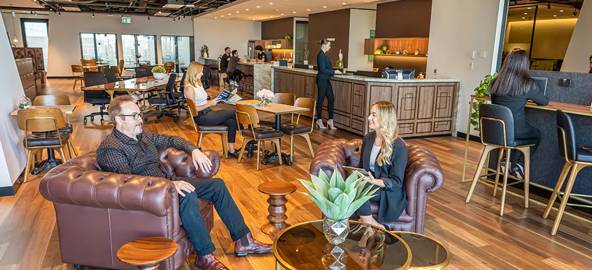 Coworking Space at Qubic Square with people working, modern desks, kitchen area, and a staffed reception.